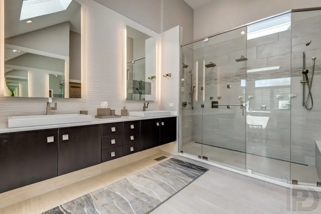 A bathroom with dark brown cabinets and two huge mirrors