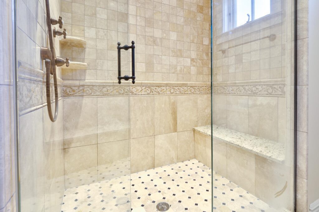 A shower area with beige walls and glass cover